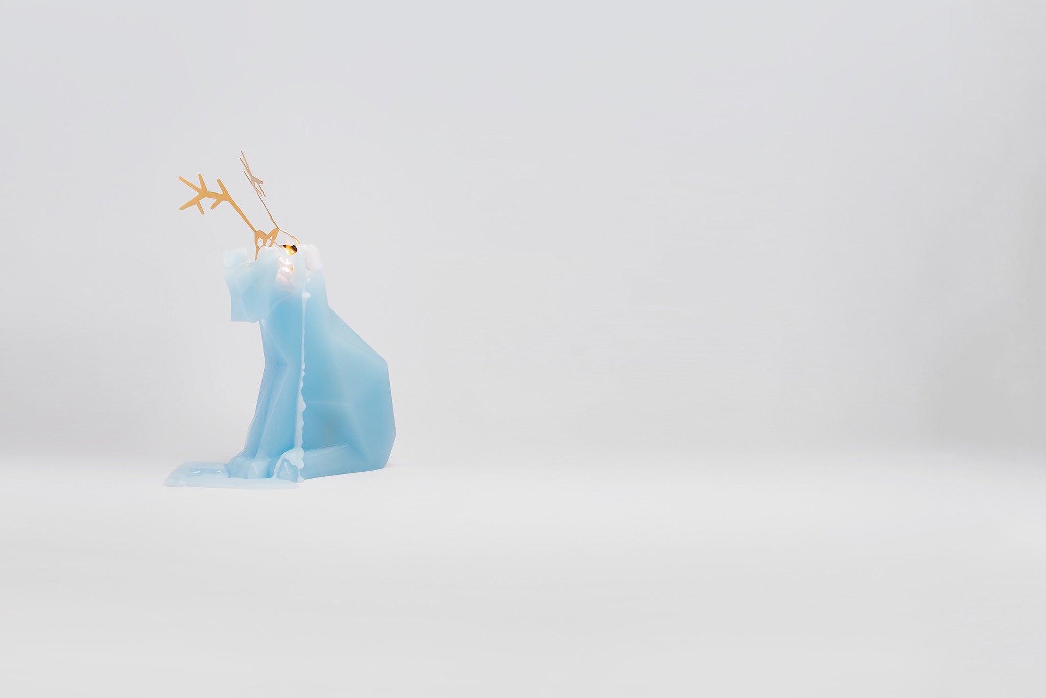 Side view of light blue dyri reindeer pyropet candle. It is starting to burn and revealing the surprise skeleton inside. 