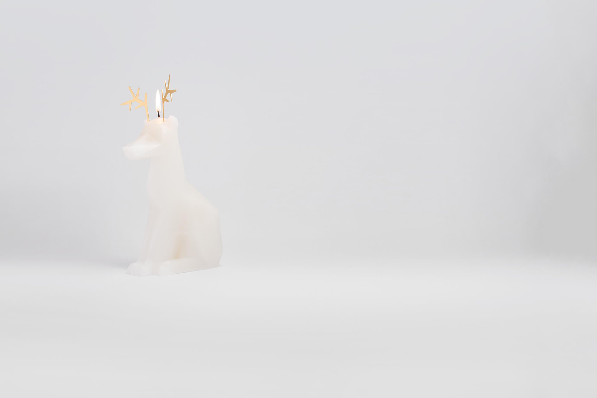 Side view of white dyri reindeer pyropet candle. It is starting to burn and revealing the surprise skeleton inside. 