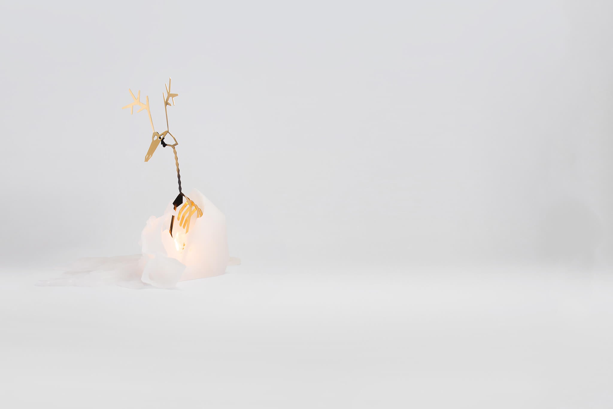 Side view of white dyri reindeer pyropet candle. It has been lit and is melting to reveal skeleton frame to keep!